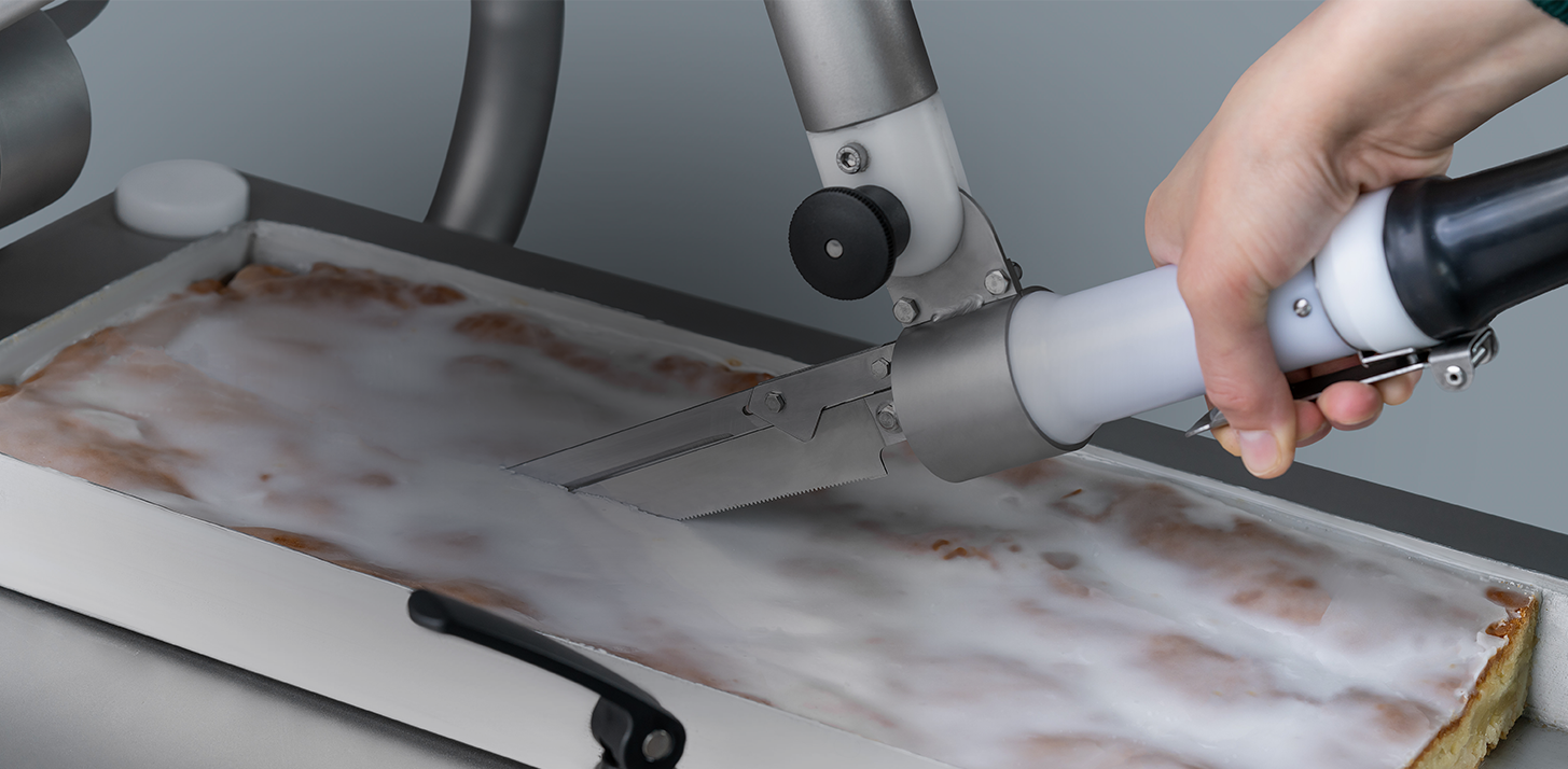 Detailansicht des RASTORs. Der Zitronenkuchen wird im Blech mit dem Messer vom Kuchentisch geschnitten.